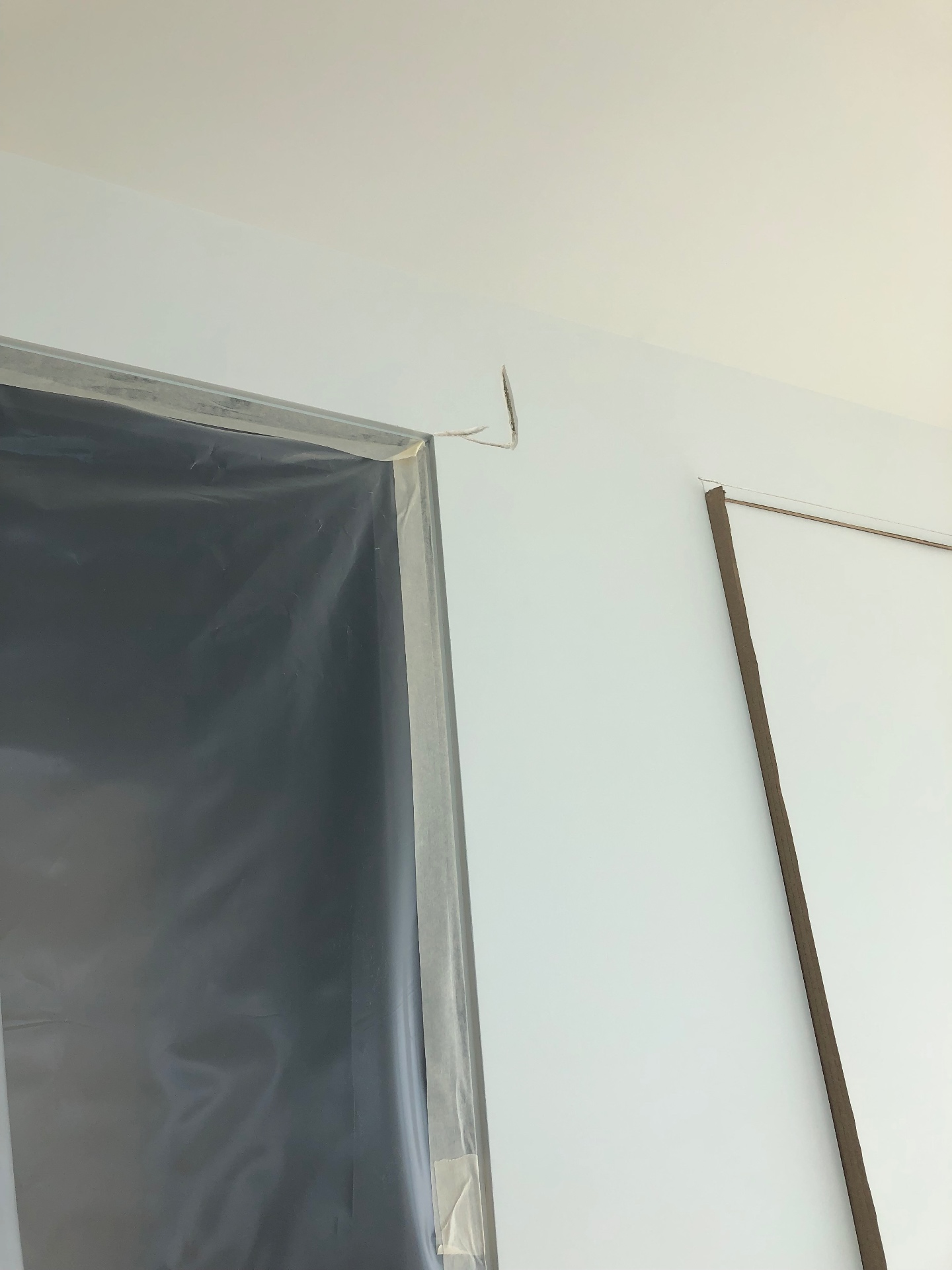 פרט של כיסוי מעבר בין חדרים — יריעת פלסטיק מודבקת בקפידה סביב משקוף